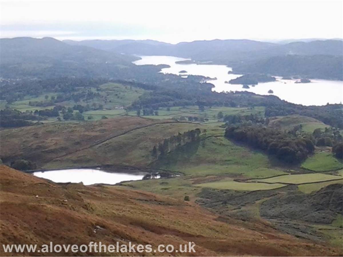Past the crags and the path swings round towards the summit, her looking back towards Windermere with the 
Dubbs Reservoir in the foreground
