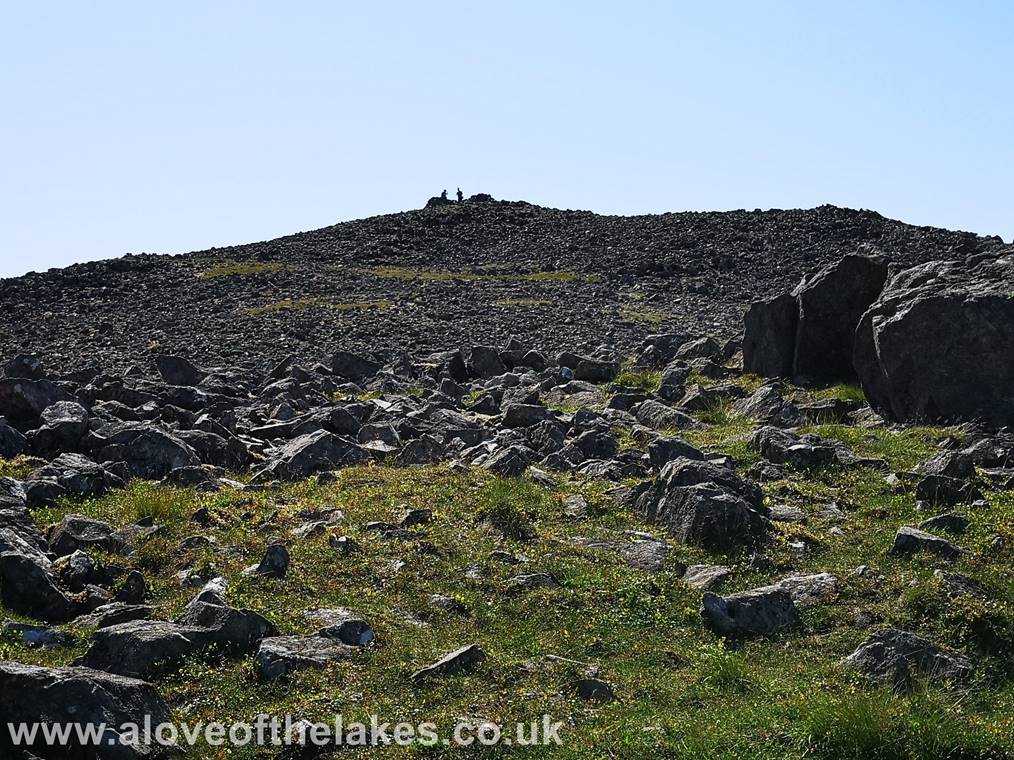 The final few yards to the summit lies across a boulder field. The shelter cairn seen in the centre of shot