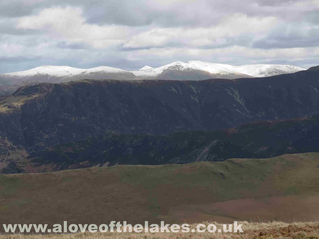 A snow capped Helvellyn range peeping over the top of Maiden Moor and High Spy