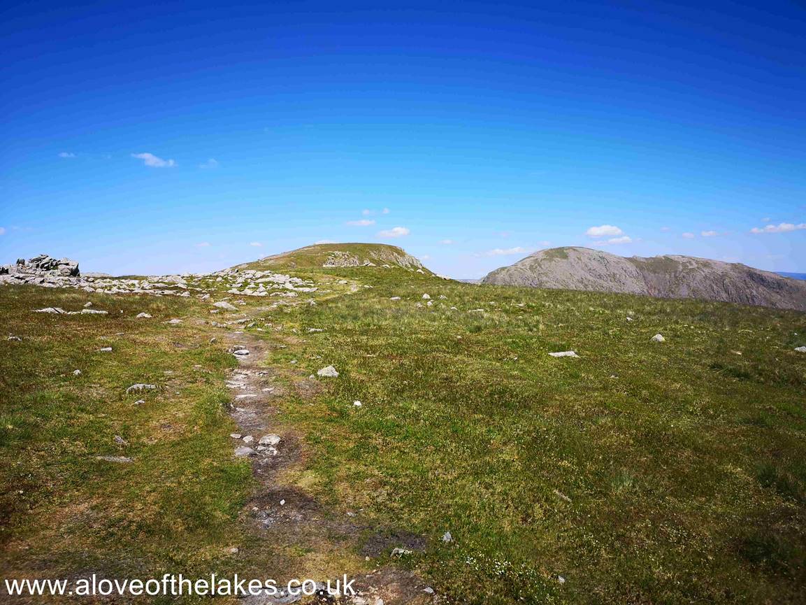 The well defined path zig zags around boulder outcrops and eventually levels out. Here the summit of Red Pike can be seen in the centre of the shot
